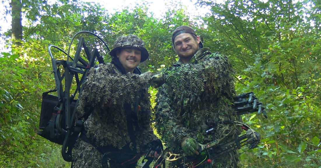 2 hunting friends wearing leafy camo suits and hats and gloves